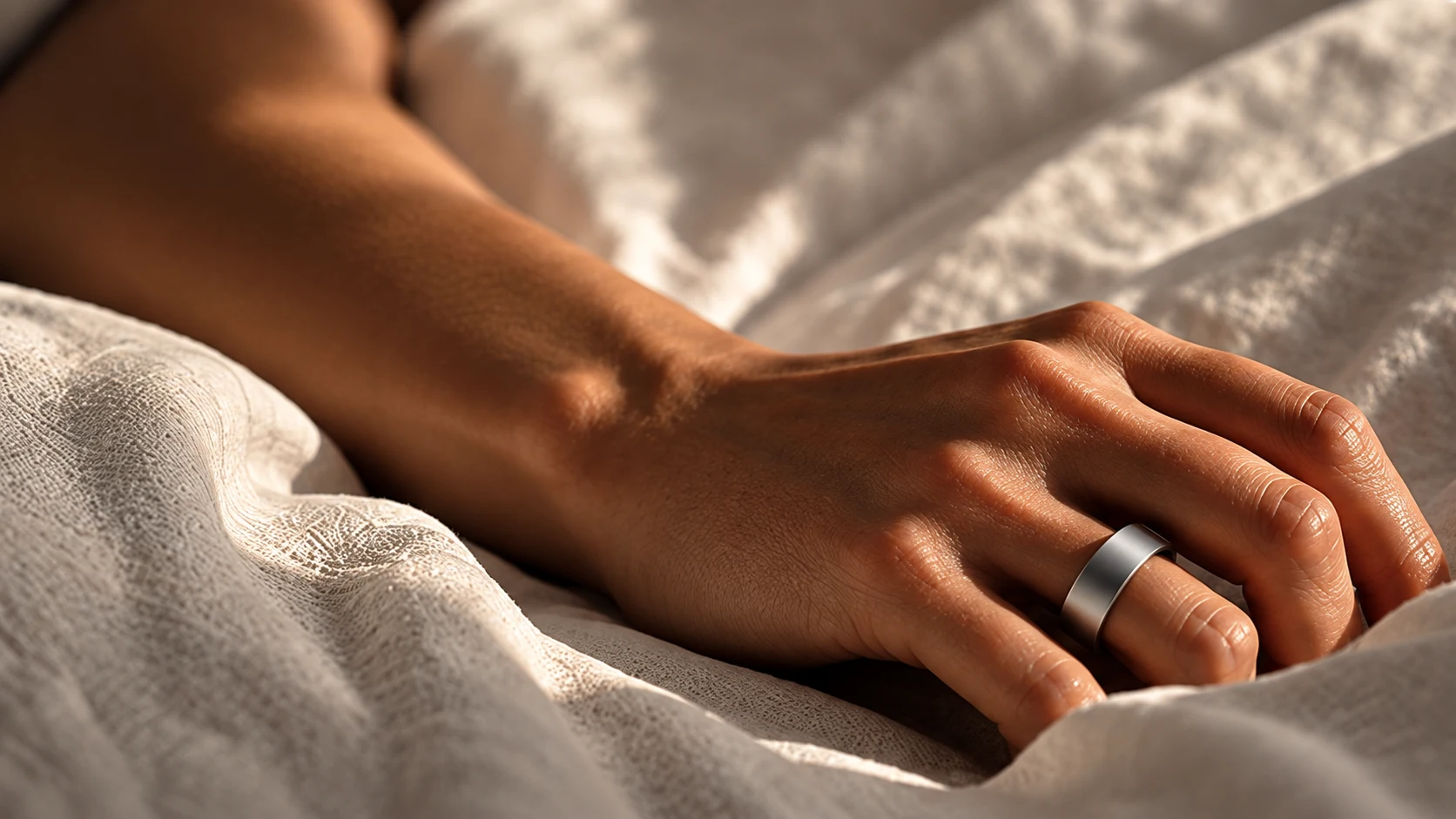 A hand wearing a silver smart ring resting peacefully on soft white bed linen in morning light